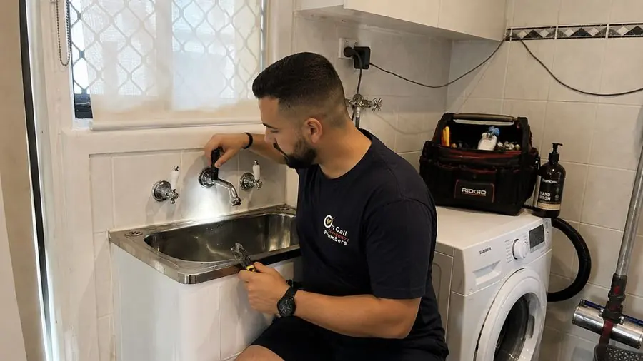 Plumber inspecting laundry tap plumbing, Mordialloc